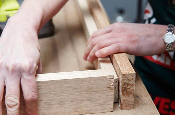 Person connecting timber frame together using glue