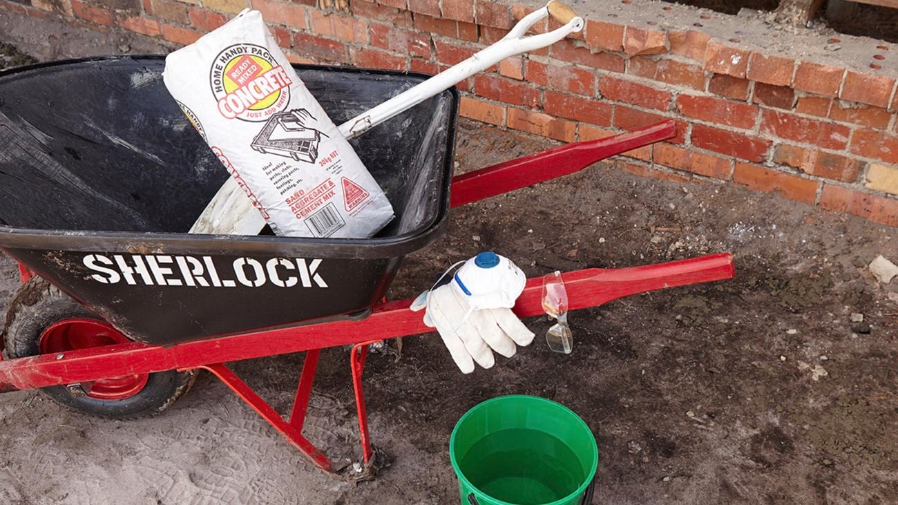 A wheelbarrow containing a bag of ready-mixed concrete