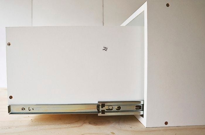 Side of white kitchen cabinet with drawer pulled out