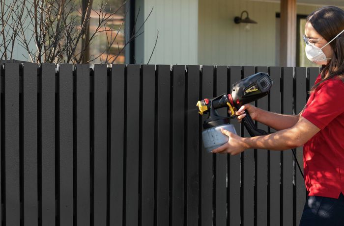 Applying multiple light coats of paint to a picket fence​​