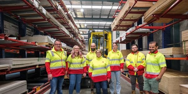 Shot of trade centre team in an aisle posing in front of forklift