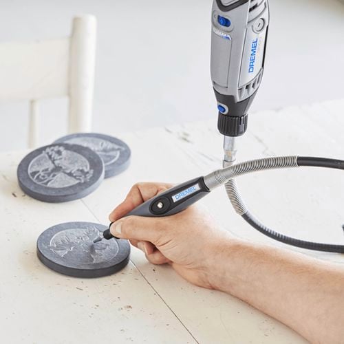 Dremel tool engraving a design on a stone coaster.