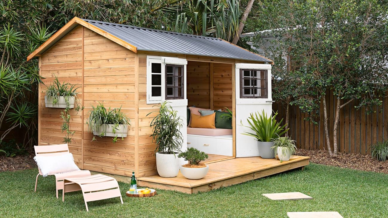 A timber garden shed and garden furniture in a backyard