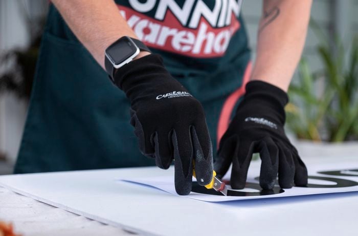 A team member using small blade to cut around stencil