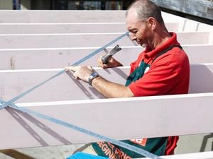 Person attaching metal cross bracing to rafters