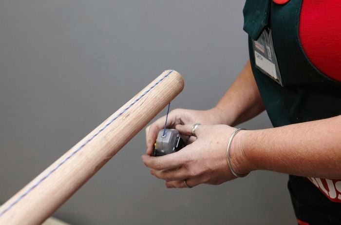 Person using chalk line to mark middle of timber dowel.