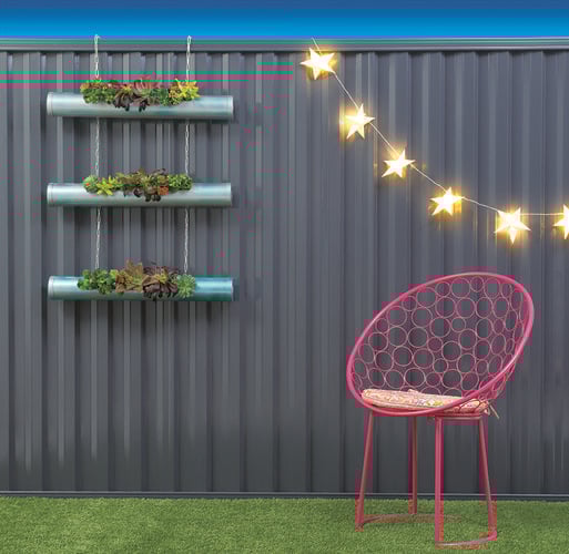 A set of small planters and star shaped light garlands hanging from a metal fence