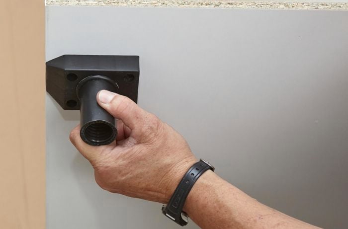 Person attaching plastic foot to panel.