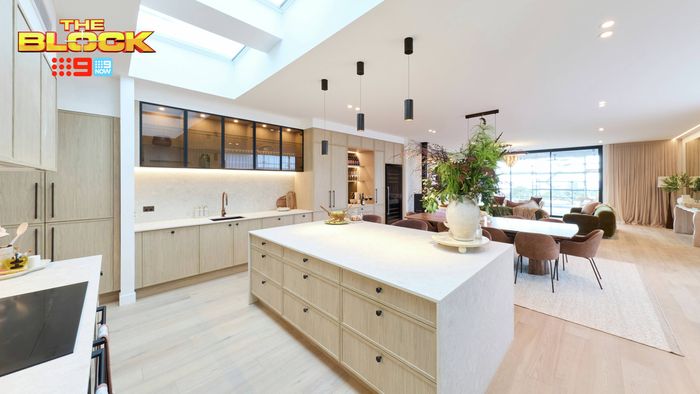 Modern open-plan kitchen and dining area featuring a large island bench, light timber cabinetry, pendant lighting and skylights.