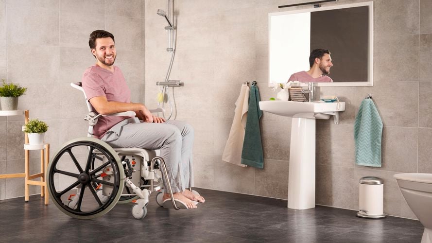 Man in wheelchair, he has a carer with him assisting in the bathroom
