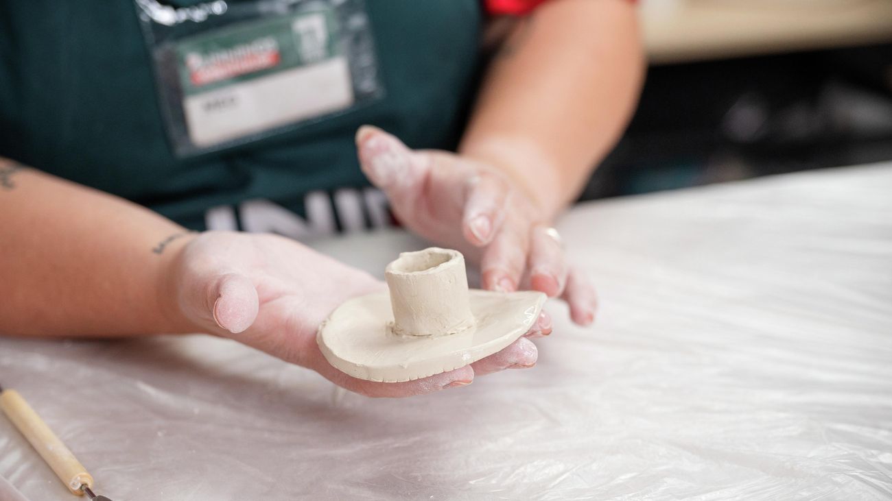 A bunnings team member smoothing out clay design.