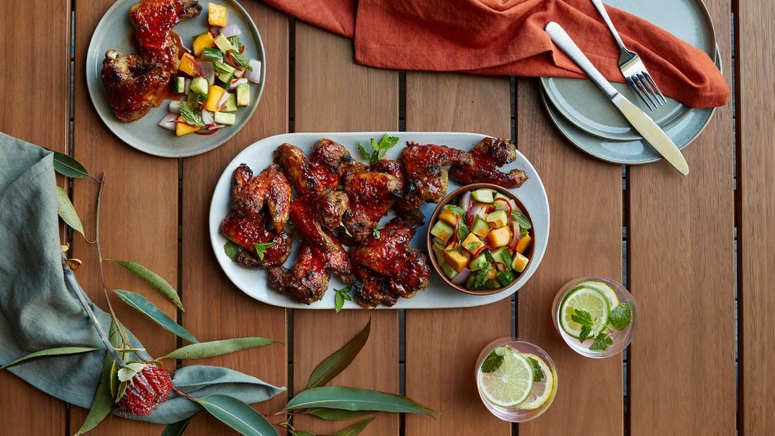 A plate full of sticky chicken wings, served with chilli mango salad