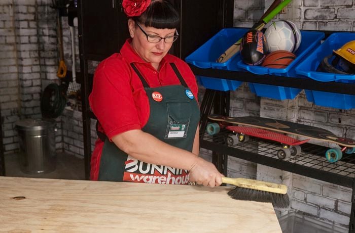 A person brushing down a plywood sheet