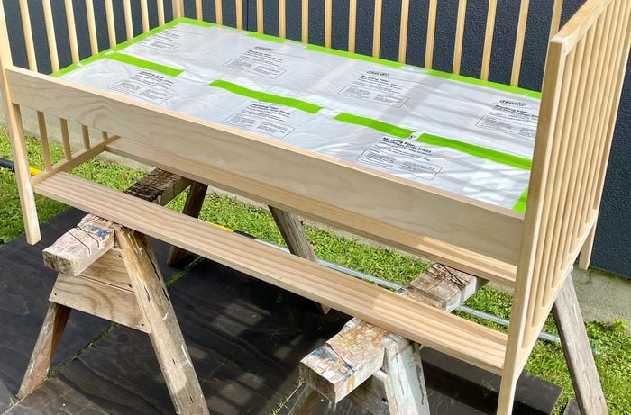 Updated wooden cot positioned on top of sawhorses underneath timber surface and grass
