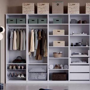 A large open wardrobe unit with shelves and hanging rails holding clothes, shoes, folded towels, storage boxes, wicker baskets, drawers and boxes on top. A floor lamp stands on the left.