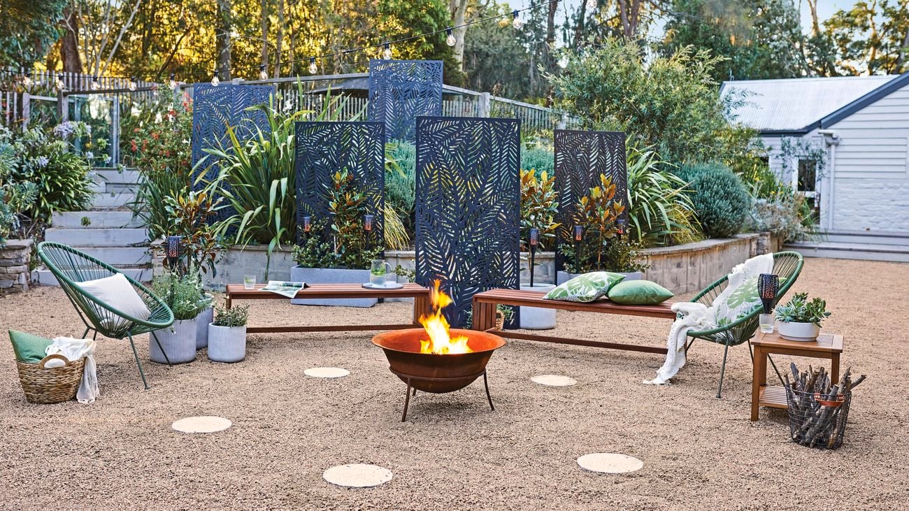 Backyard with a fire pit, screen panels and chairs in it