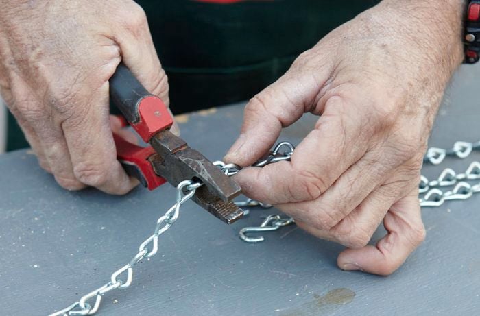 A length of chain being cut to the required length with pliers