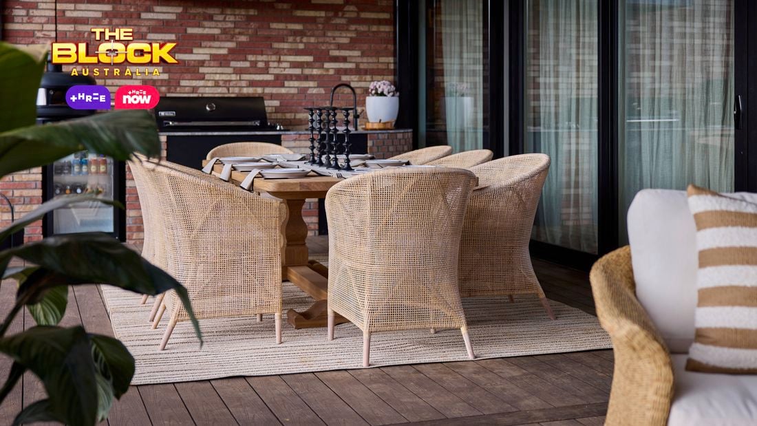 An outdoor area with a table and chairs around it in front of a barbecue.