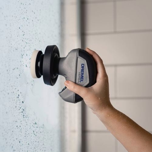 Hand cleaning a tiled wall with Dremel Versa scrubber.