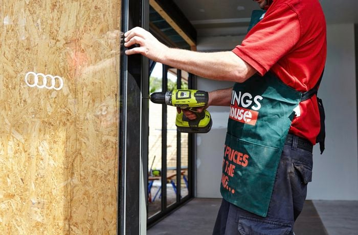 French doors being secured into place by a Bunnings team member with a power drill