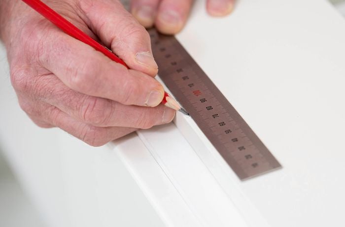 A person holding a pencil next to a ruler on a kickboard.