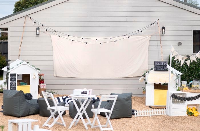 Outdoor furniture in front of a wall with canvas screen and fairy lights