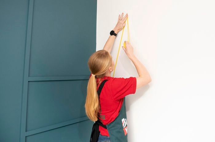 Person taping lines on wall.