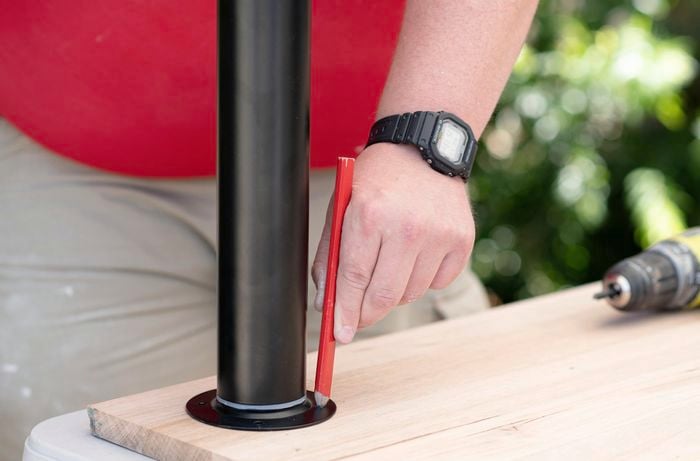A Bunnings team member tracing the outline of a table leg onto a piece of timber with a pencil