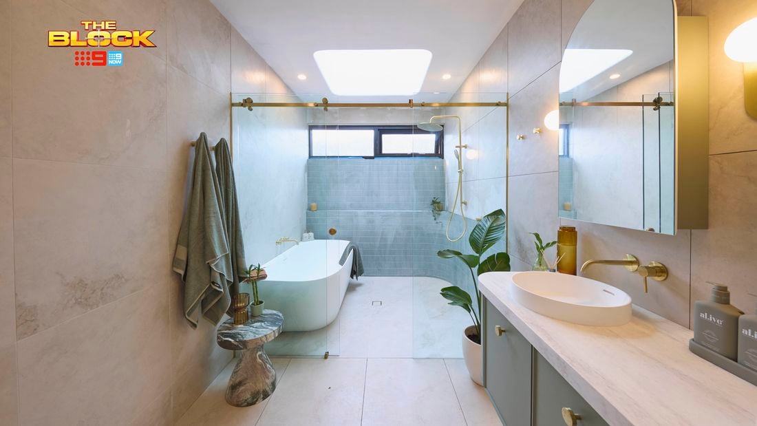 Green, gold and white coloured bathroom with a timber fluted profile vanity and marble benchtop and bath
