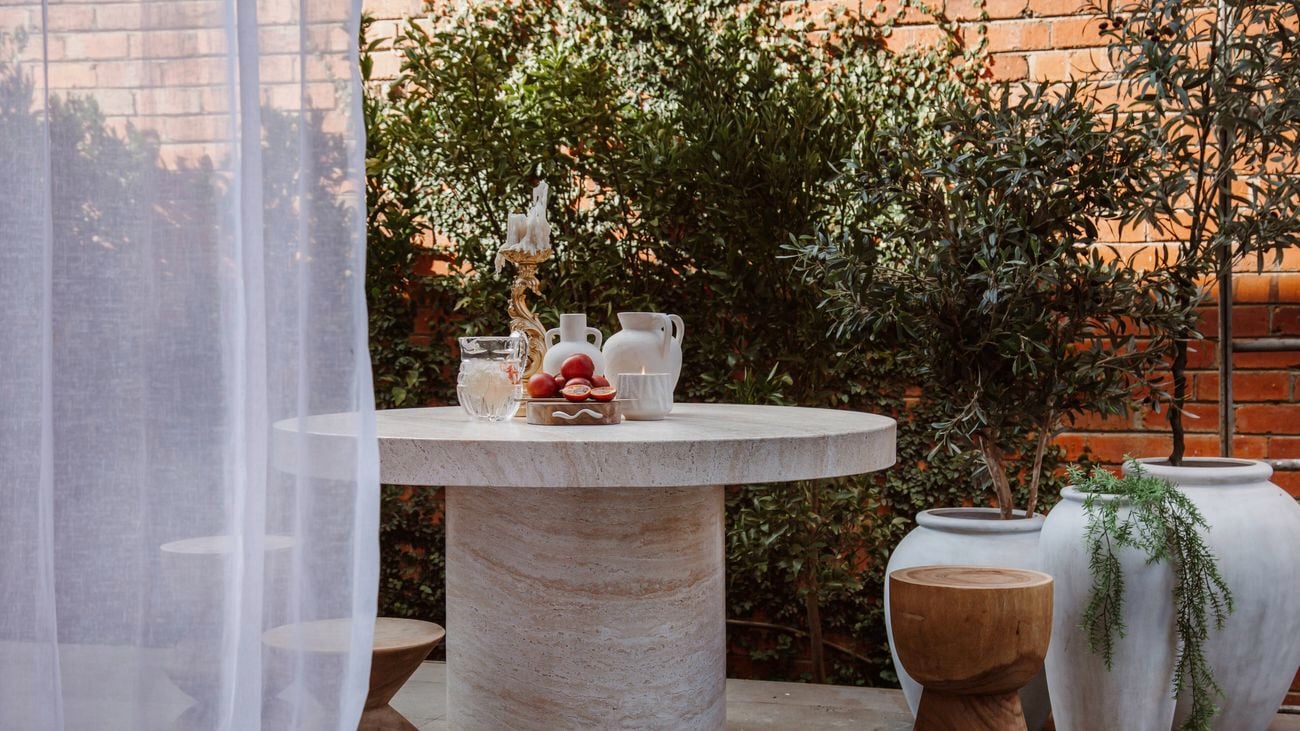 Outdoor table in front of a brick wall and plants