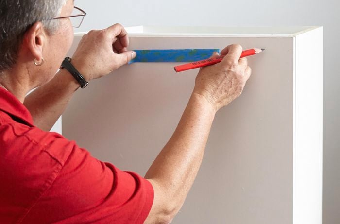 Person using tape and pencil to mark up linen chute cupboard.