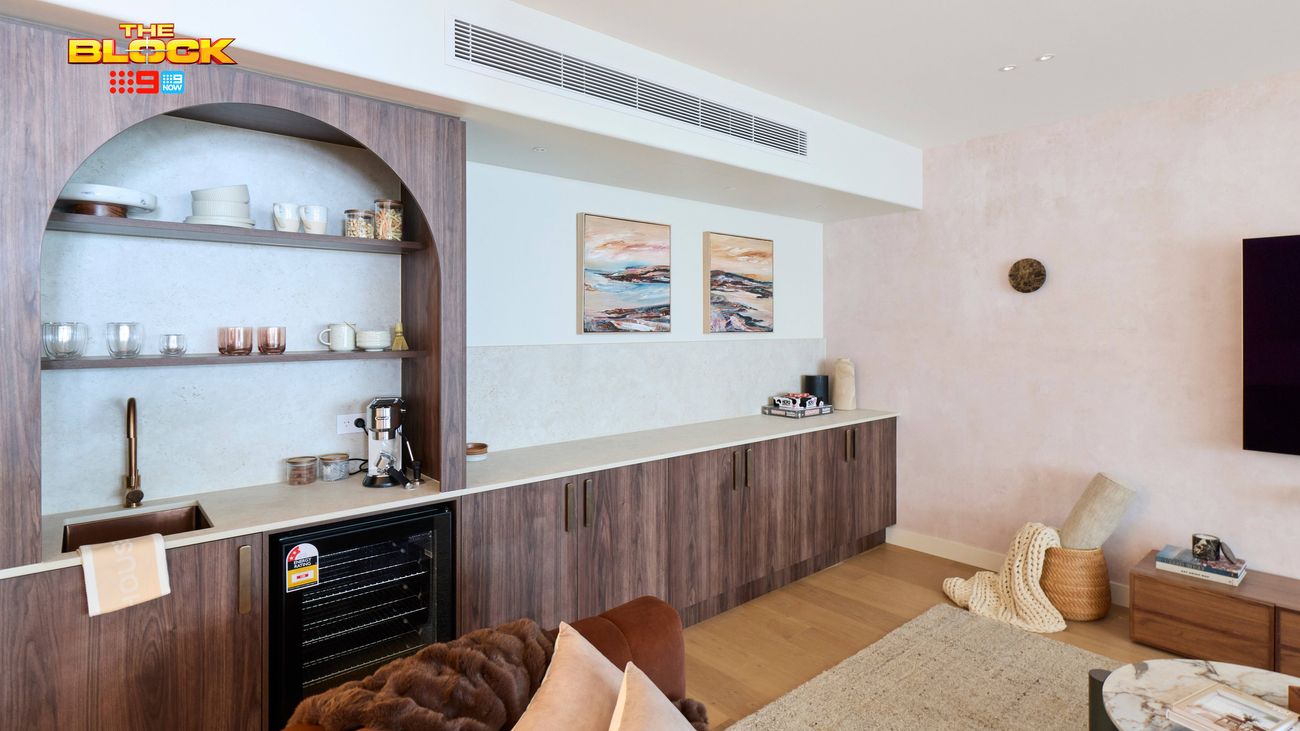 Built-in home bar featuring dark timber cabinetry, arched open shelving, stone benchtop, sink and beverage fridge.