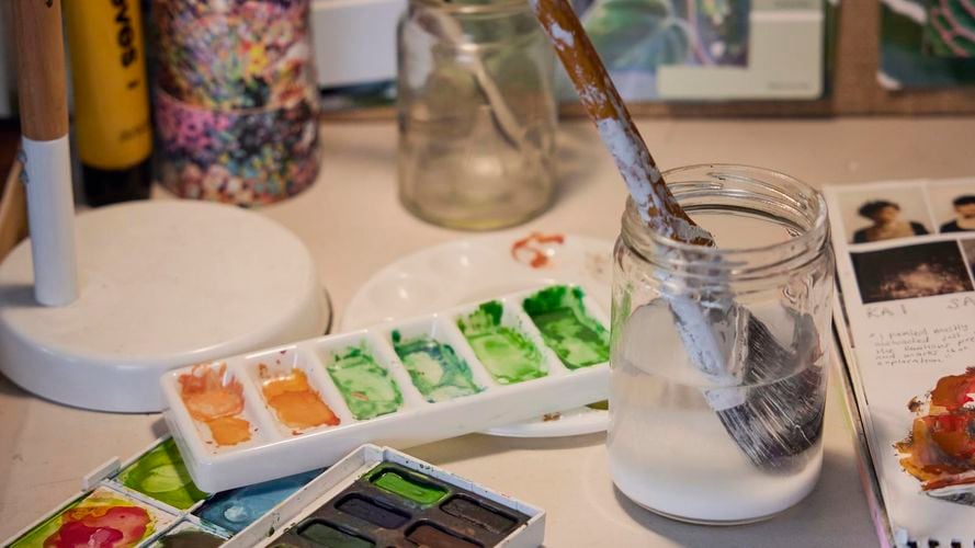 Painting palette and brushes in jars on a workbench