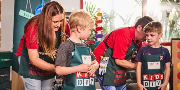 Bunnings Team Member's putting aprons on Children in a Bunnings store.
