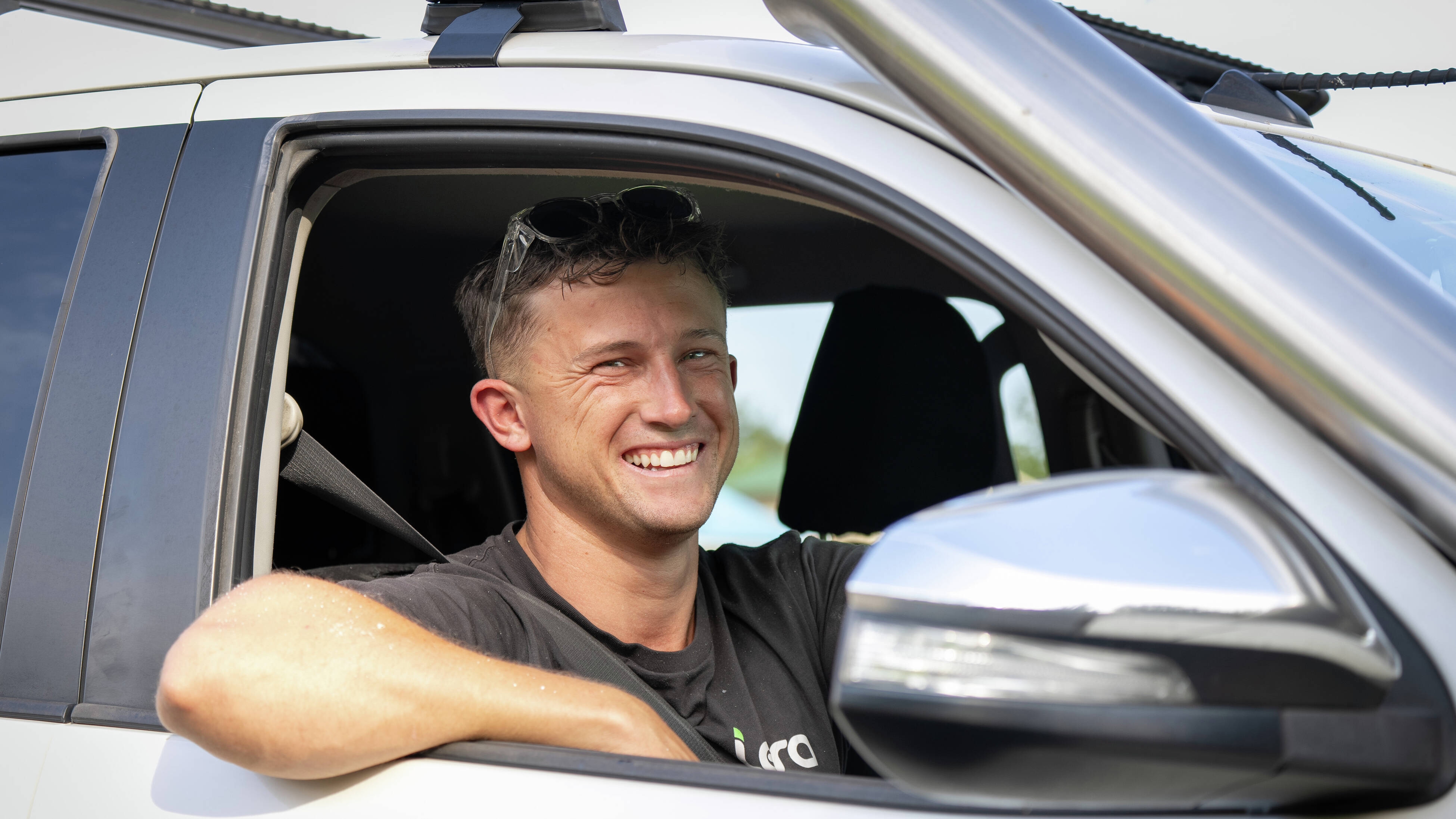 : A close up of tradesperson smiling out their car window