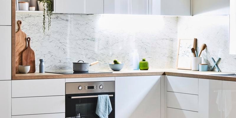 Wide shot of a kitchen featuring appliances, sink and crockery.