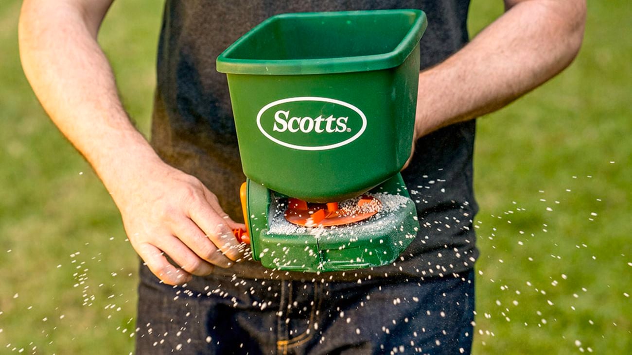 Person using Scotts hand held fertiliser spreader