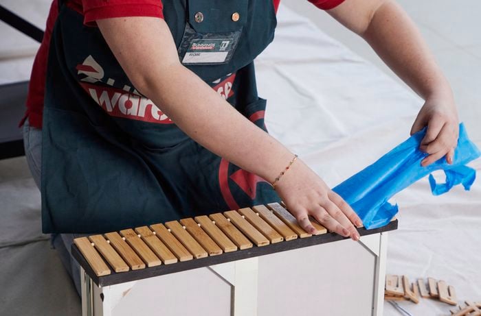 Person removing blue tape from wooden slats.
