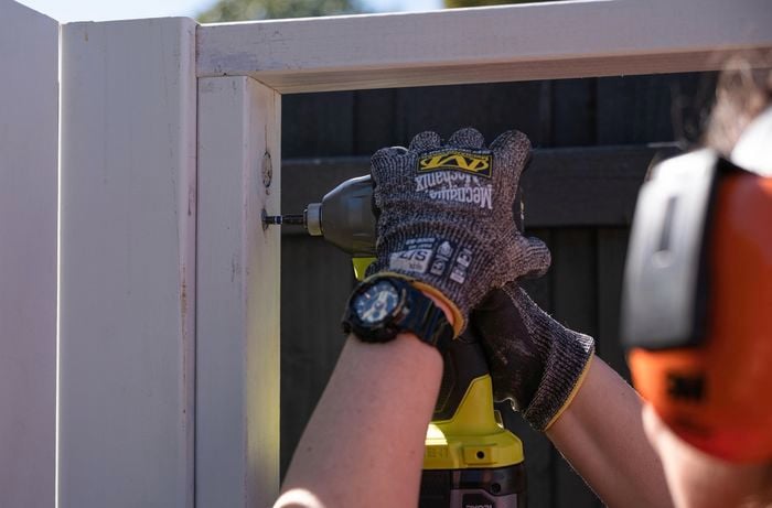 person using a hand drill to attach timber post together