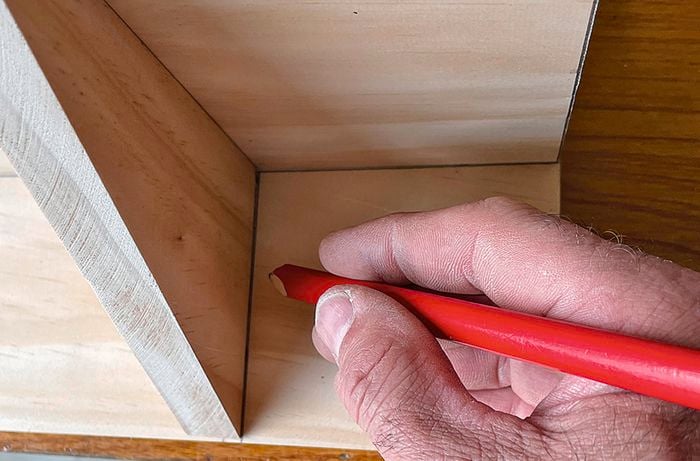 A person marking a piece of wood with a pencil