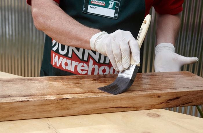 Person painting timber wall shelf with varnish.