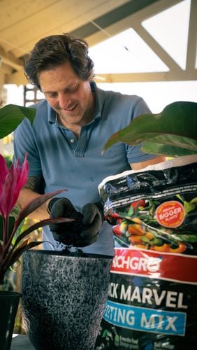 Man putting potting mix from bag into pot. 