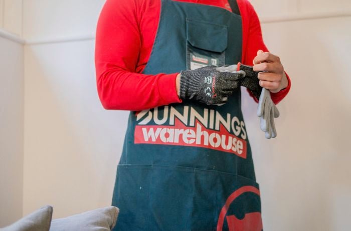 A Bunnings team member putting on protective gloves