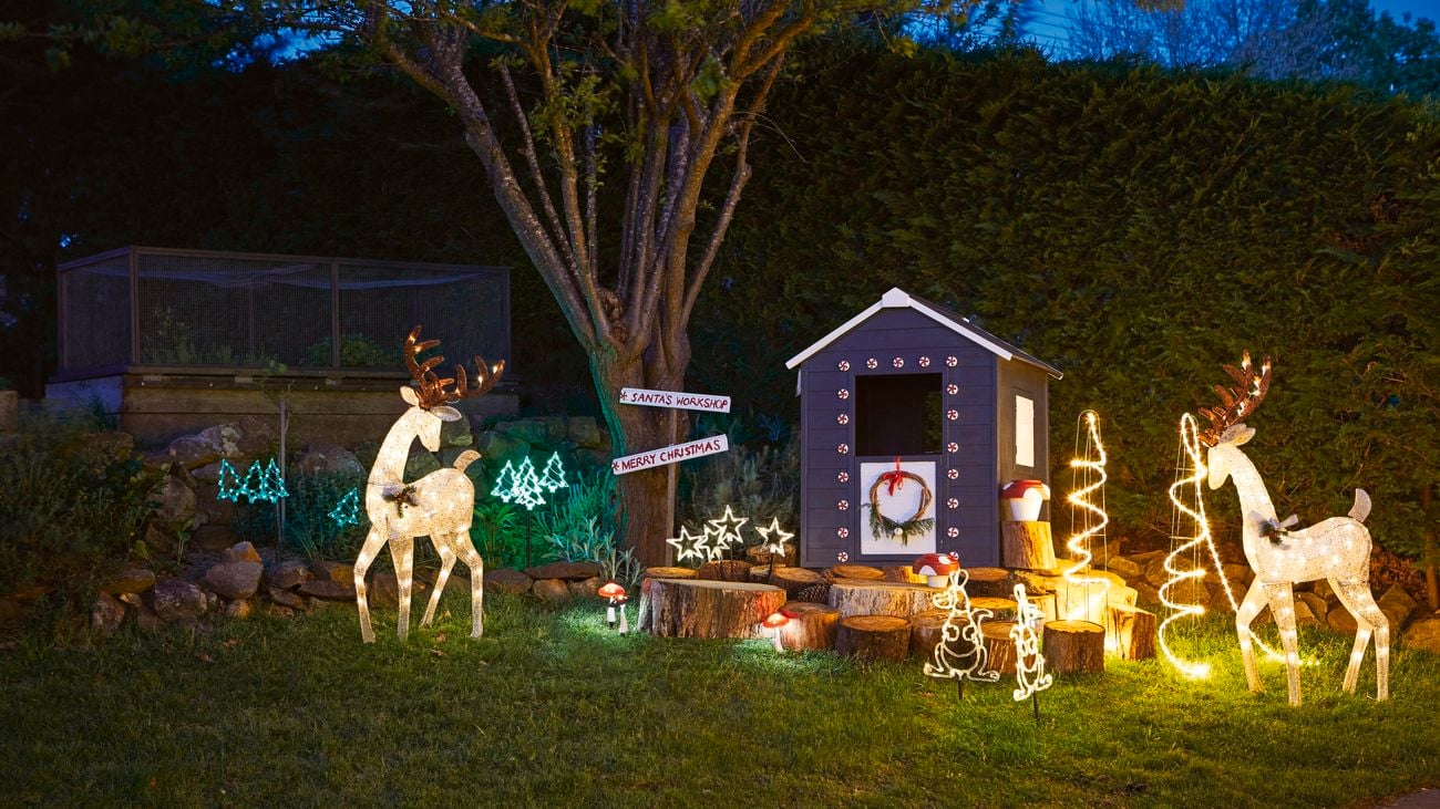 Illuminated reindeer, kangaroos and stars next to a decorated cubby house at night