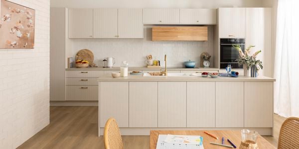 Soft Coastal kitchen with light groove cabinets, timber rangehood, gold tapware, and airy natural light