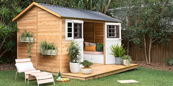 A timber garden shed and garden furniture in a backyard