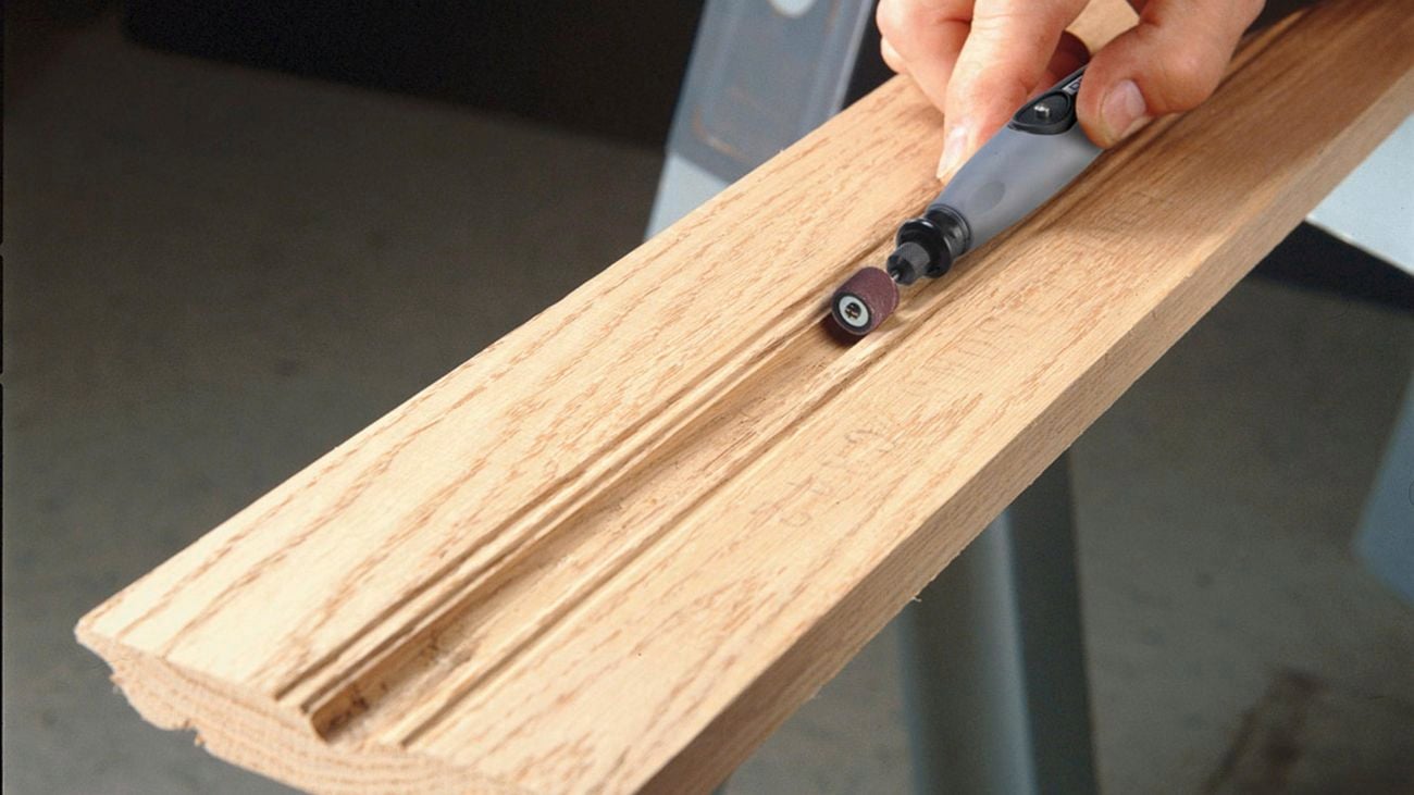Person using the Dremel 225 flex shaft attachment to sand the divet in a plank of wood