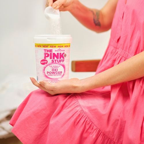 A woman scooping some Oxi Powder from a container.
