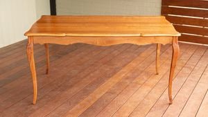 An image of a restored wooden table with a smooth finish is placed on a timber deck.