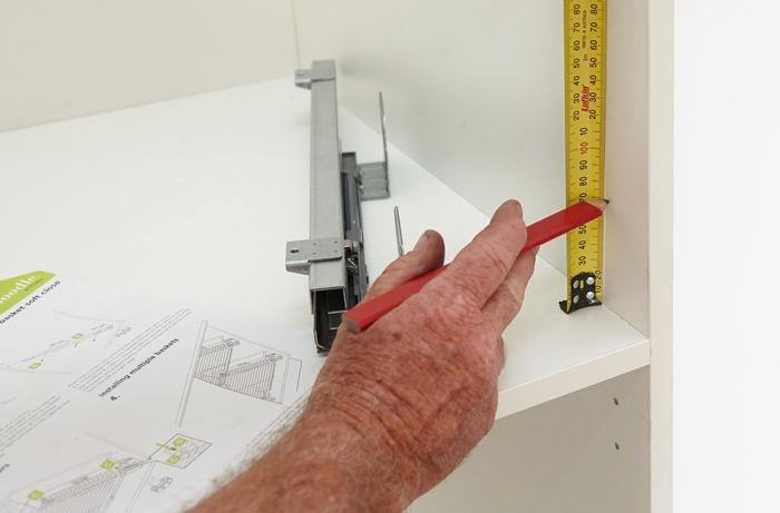 Person measuring inside of cupboard with measuring tape.